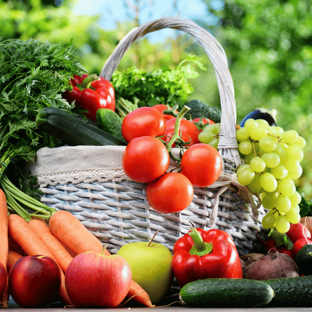 Esta imagen muestra una cesta blanca llena de frutas y verduras frescas